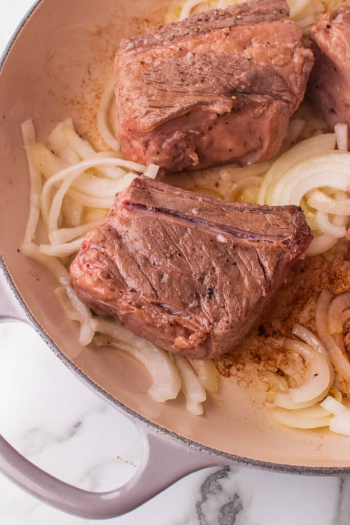 Bife refogado e cebola em uma frigideira.