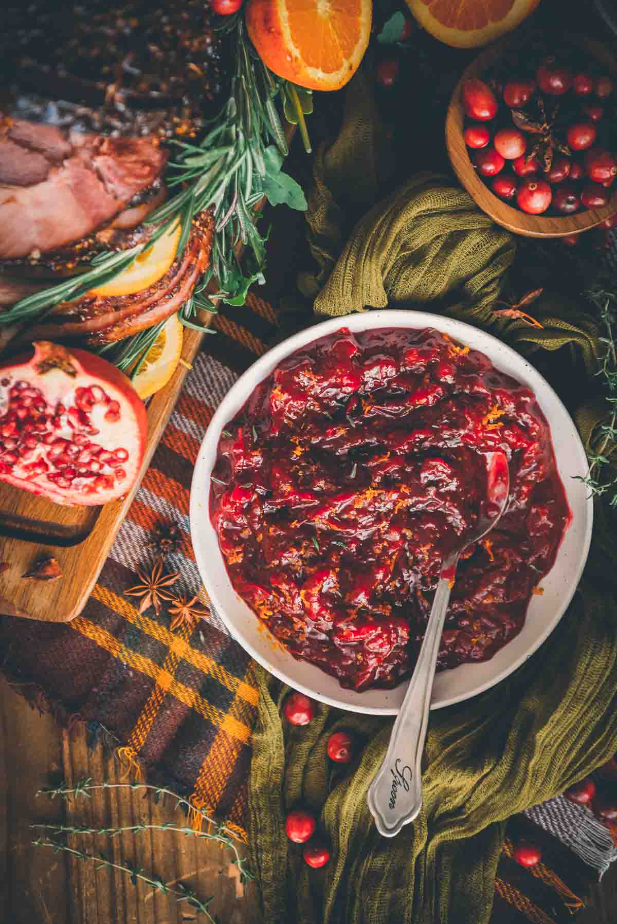 Foto aérea de molho caseiro de ceto cranberry em uma mesa festiva decorada com outros alimentos sazonais. 