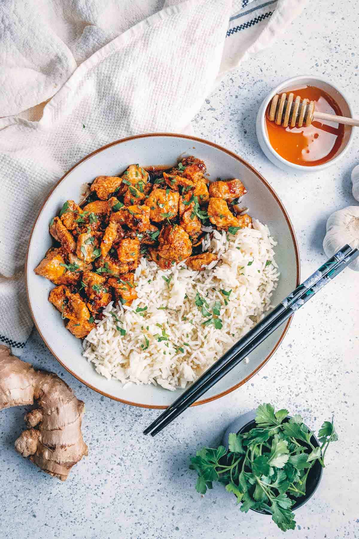 Uma tigela de pedaços de frango frito e arroz com gengibre e alho.