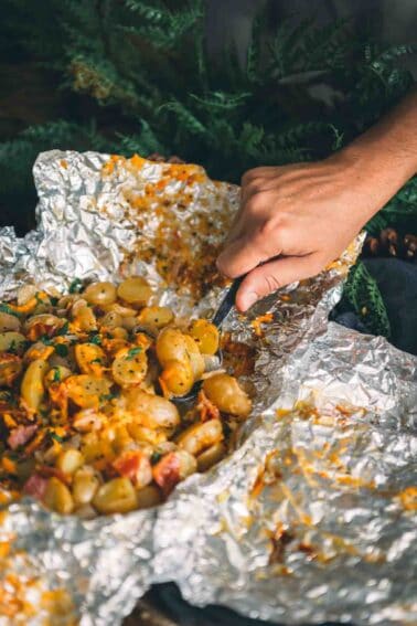 Uma pessoa está preparando batatas para fogueira.
