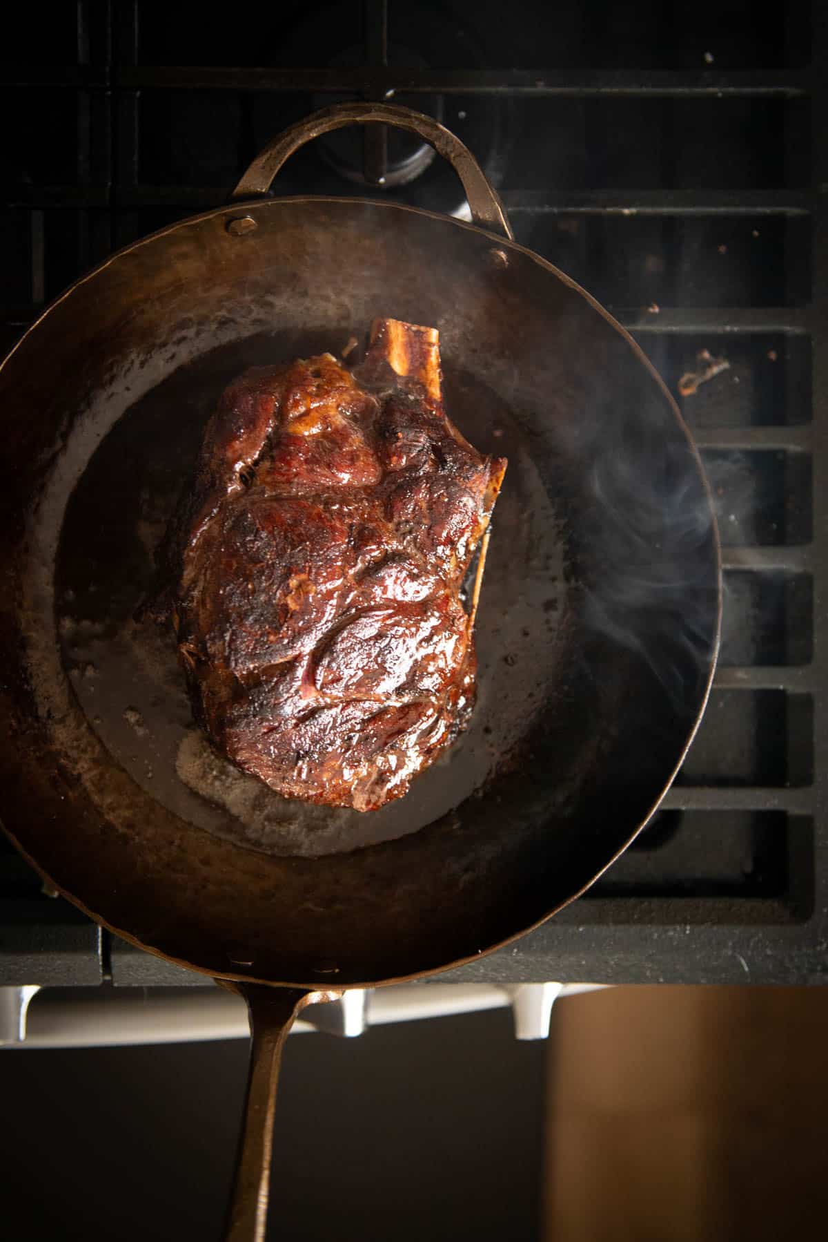 Um bife grelhado cozinhando em uma frigideira de aço carbono no fogão.