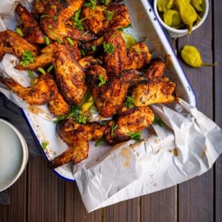 prato de asas de frango salgadas com leitelho esfregado com especiarias e pimenta-do-reino ao lado e molho rancho