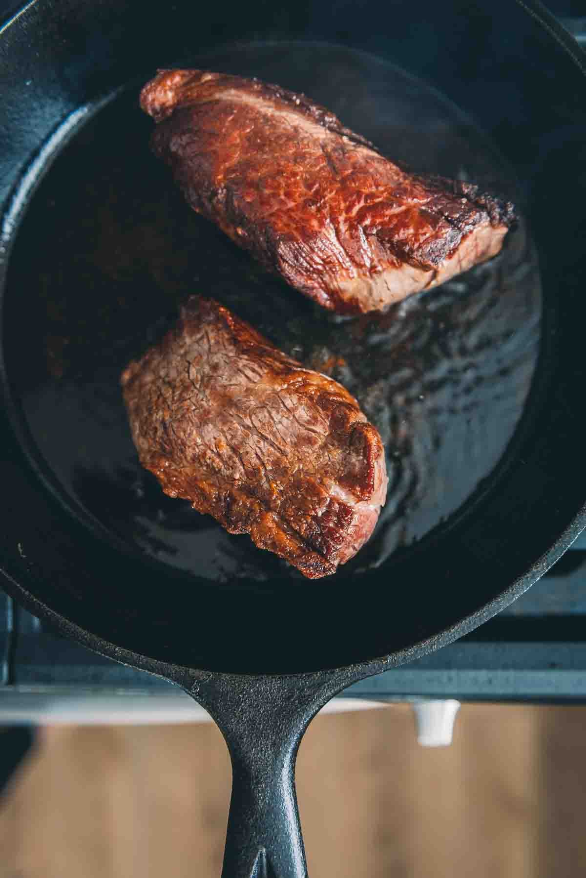 Sobrecarga dos bifes em uma frigideira de ferro fundido para mostrar a selagem. 