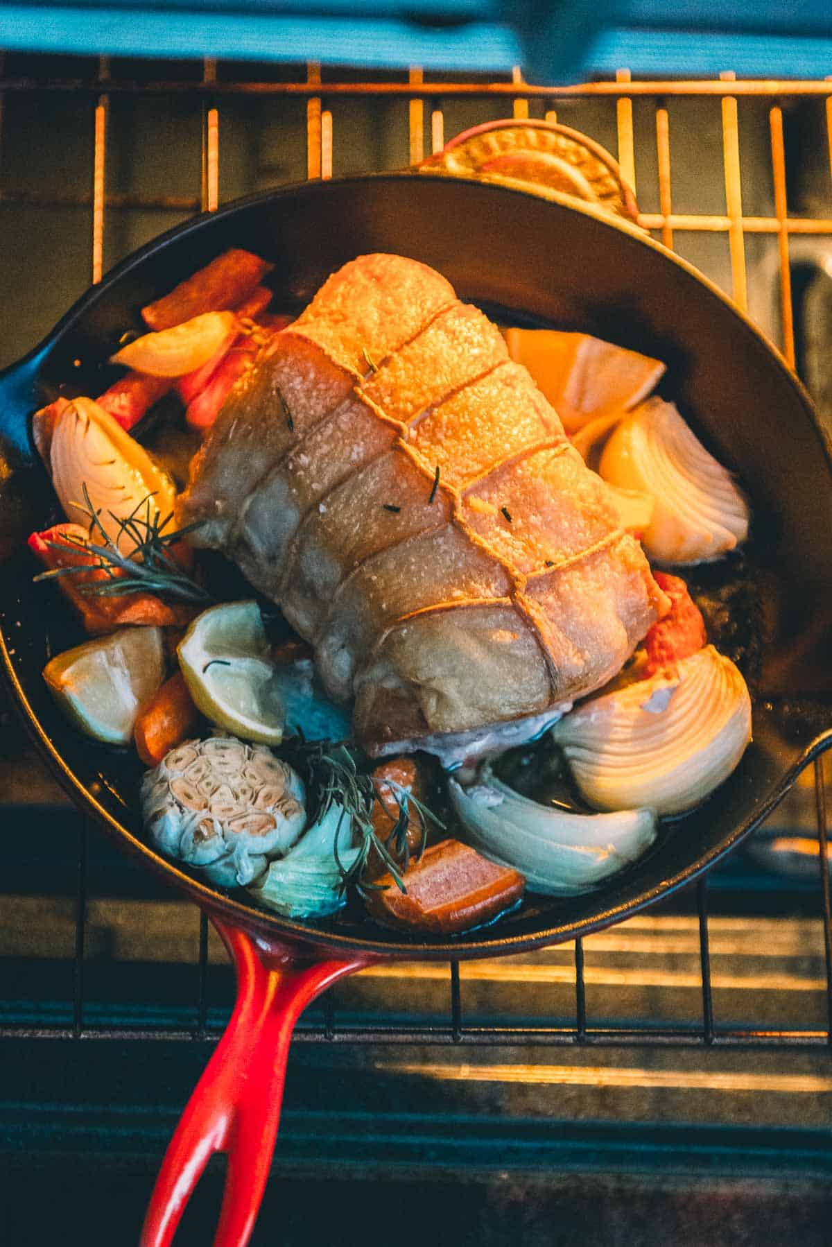 Uma frigideira com carne de porco assada e legumes a ir ao forno.