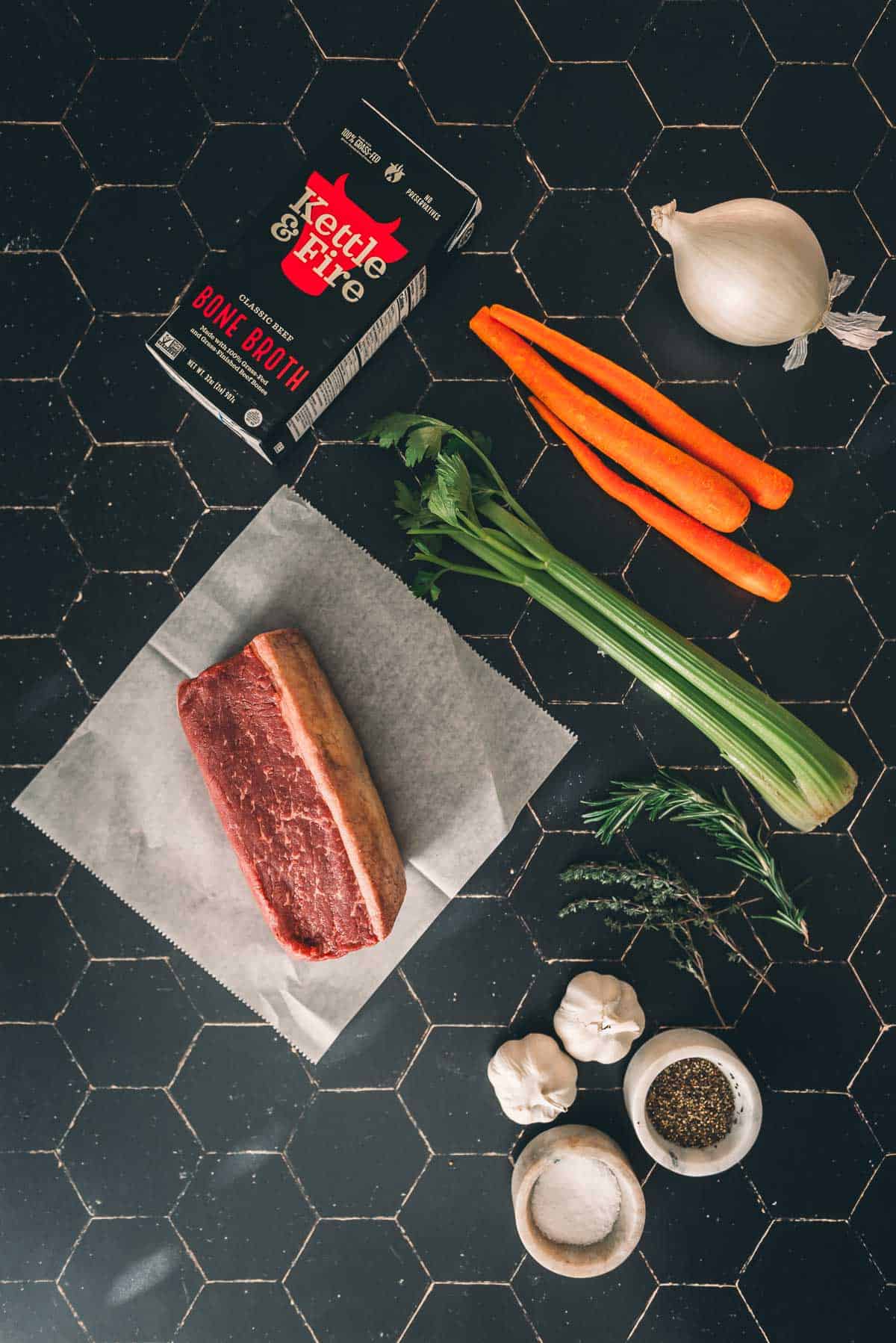 Carne, cenoura, cebola e especiarias sobre uma mesa.