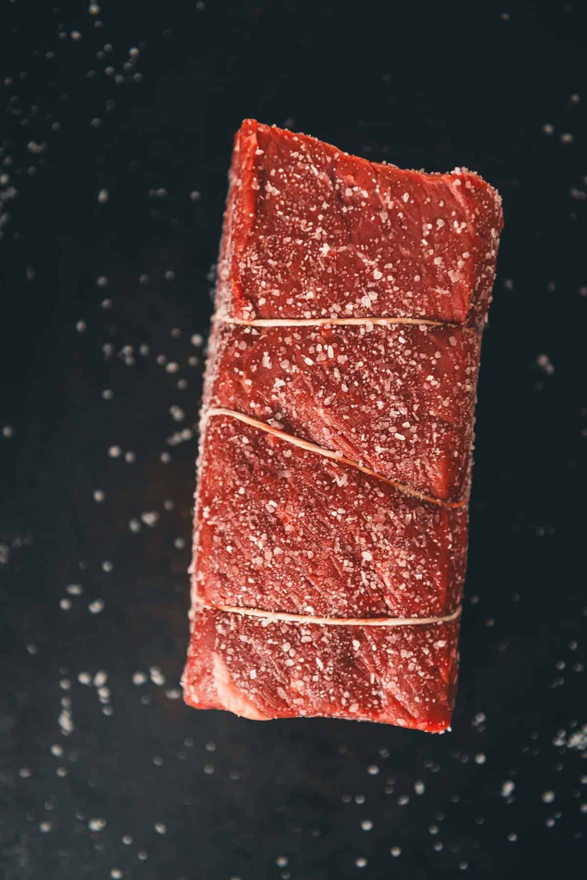Um pedaço de carne vermelha sobre um fundo preto.