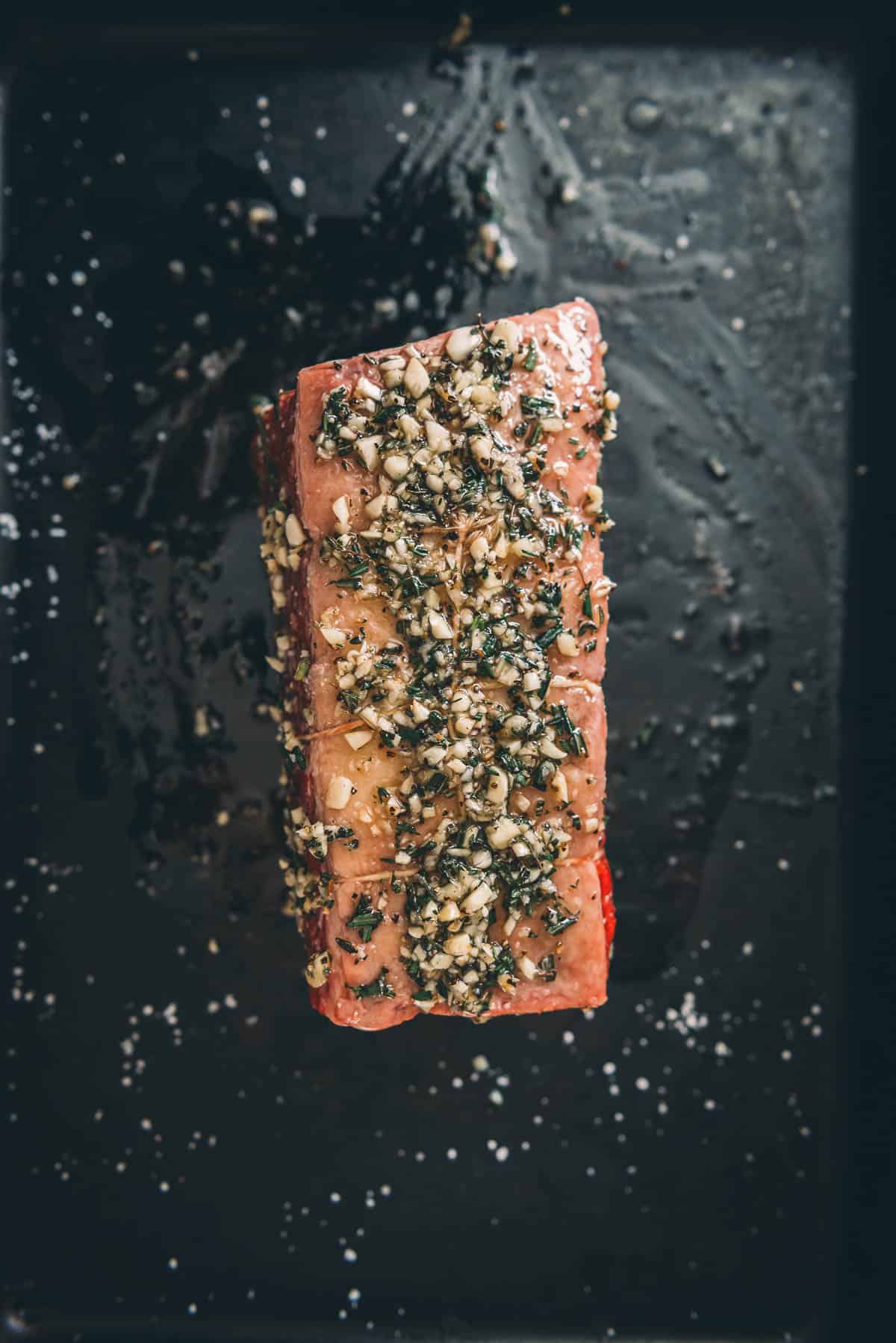 Uma carne assada em uma assadeira com ervas.
