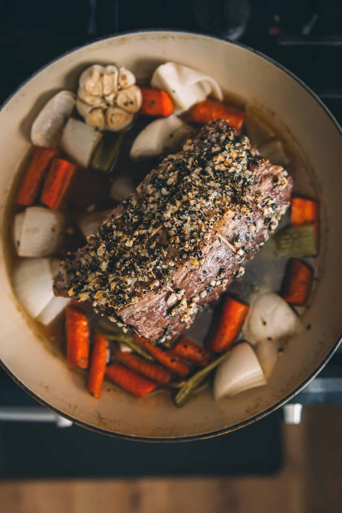 Um forno holandês cheio de carne e vegetais no fogão.