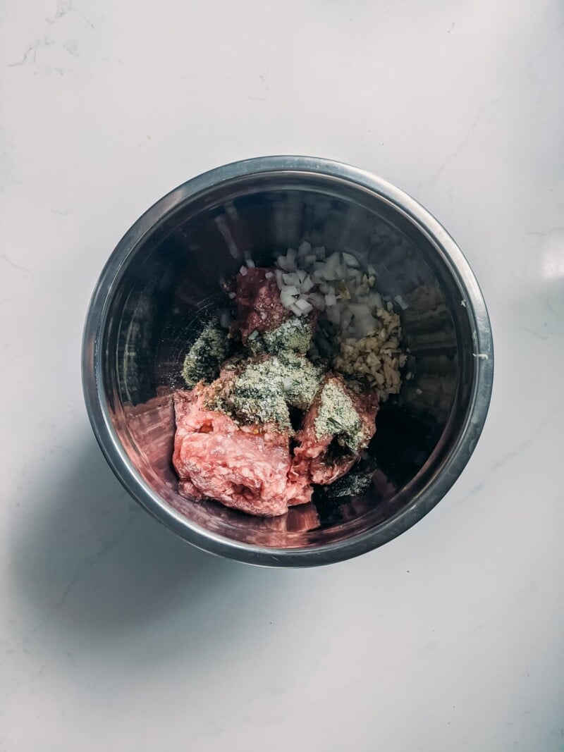 dose de ingredientes de almôndega de cordeiro em uma tigela pronta para ser misturada, cordeiro cru, especiarias, cebola picada, alho