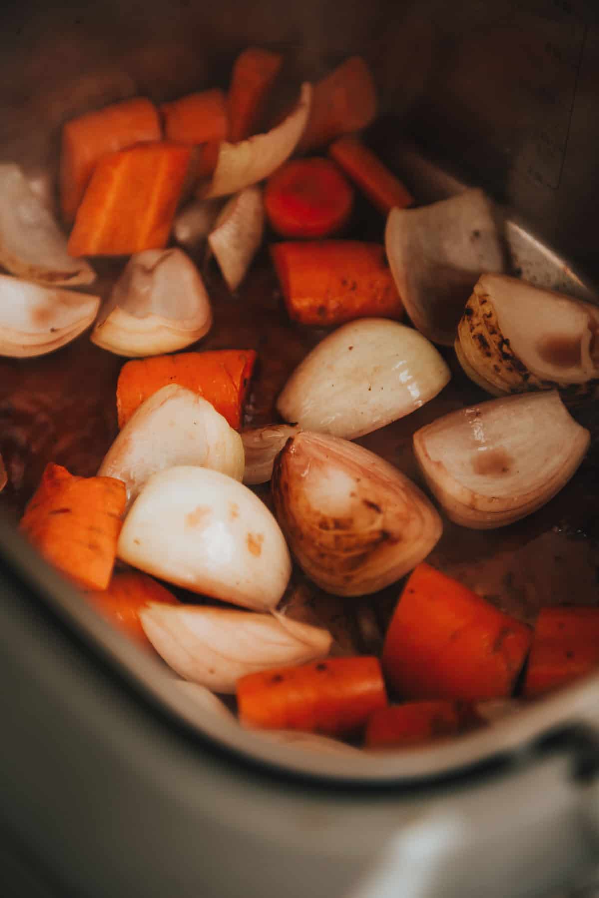 Cenouras e cebolas estão sendo cozidas em panela elétrica.