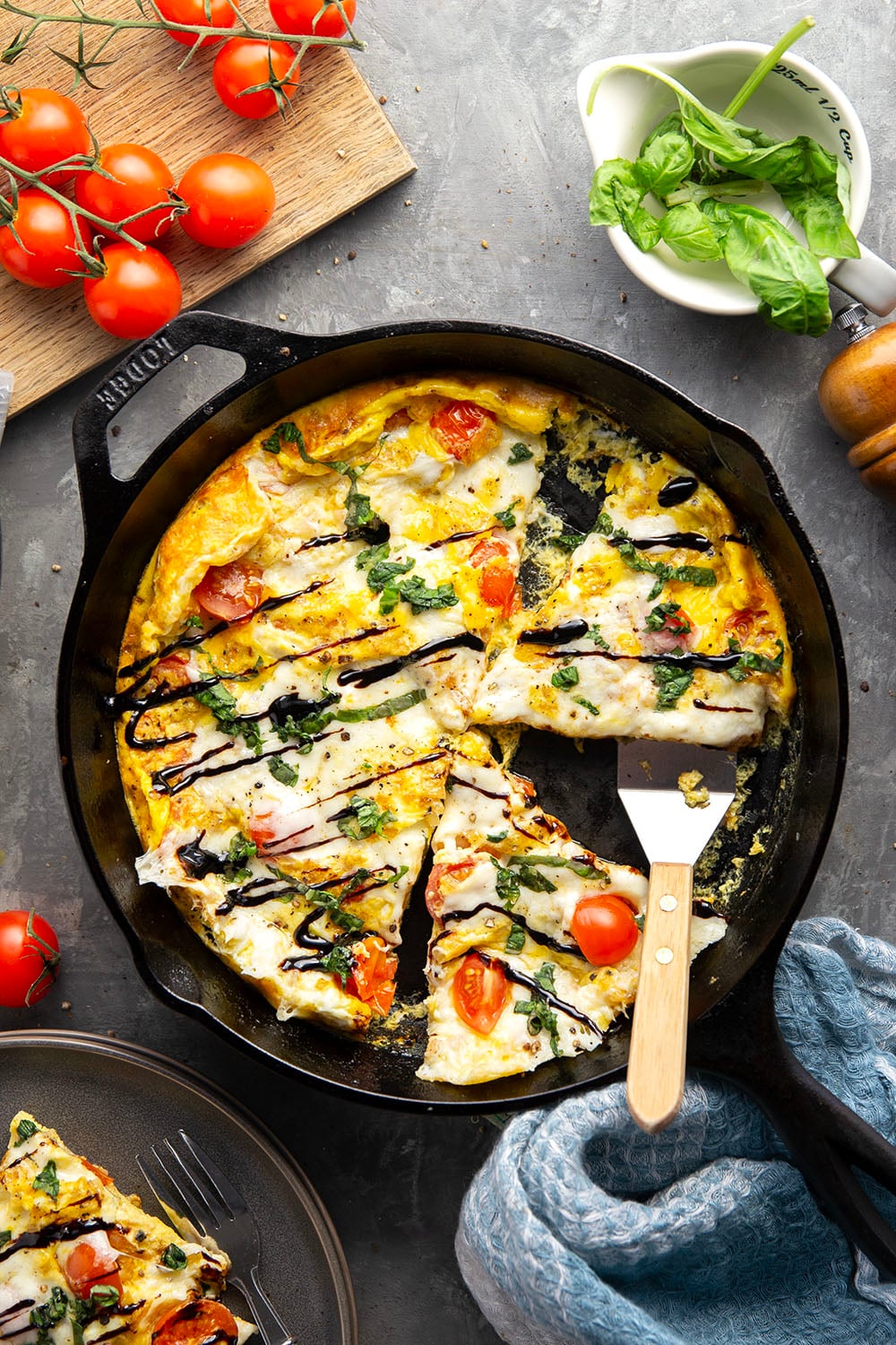 Esta fritada caprese não poderia ser mais fácil de preparar e apresenta uma base de ovos fofos, tomate cereja doce, mussarela fresca pegajosa e muito manjericão fresco e esmalte balsâmico por cima.
